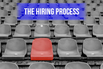 red chair among grey chairs with banner stating the hiring process
