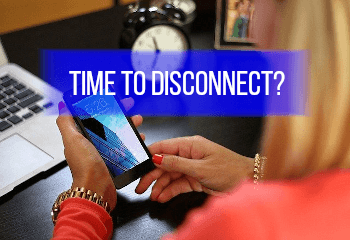 time to disconnect written on a banner with image of woman looking at her smart phone and clock in background 